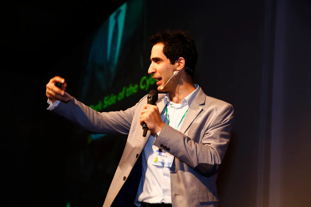 Menny Barzilay gesturing on a dark stage